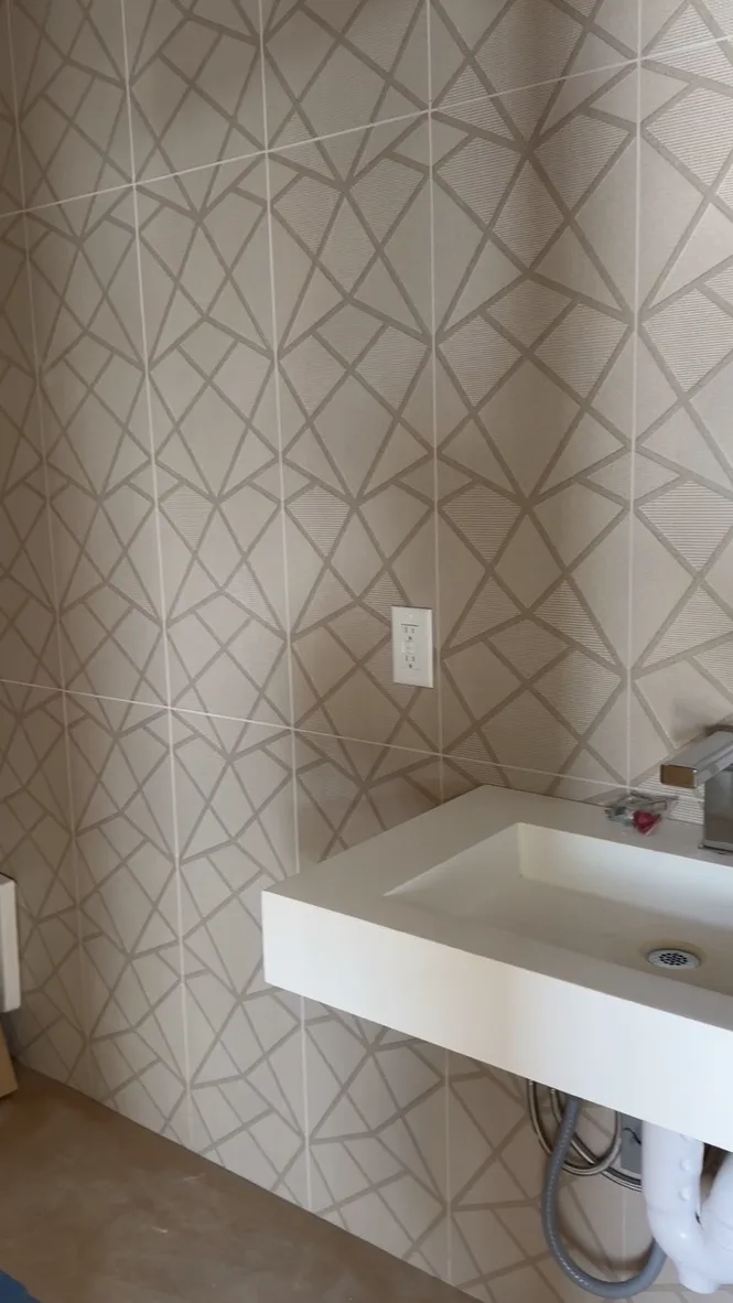 A finished restroom with a geometric patterned feature tile wall and a modern floating white vanity.